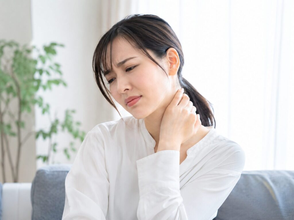 朝起きて首の痛みを感じている女性の画像