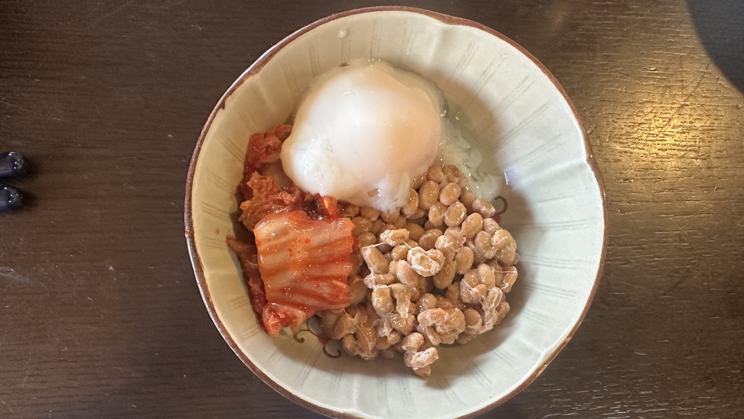 納豆にキムチと温泉卵をのせた朝ごはんの写真