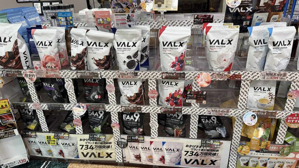 VALX棚を正面から撮った、ホエイ・HYBRID・ソイ・EAA9などがまとめて見える写真。