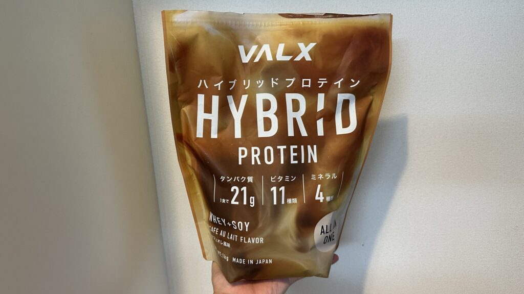 VALX HYBRID PROTEINカフェオレ風味1kgを手に持った様子